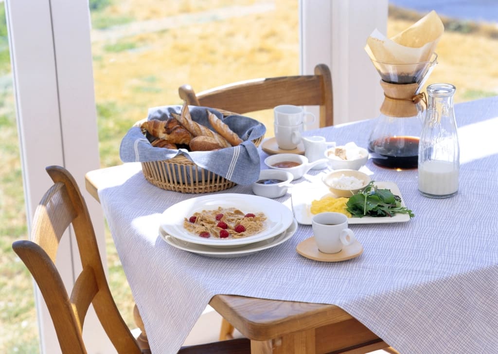A sunny kitchen table set for breakfast beside a window